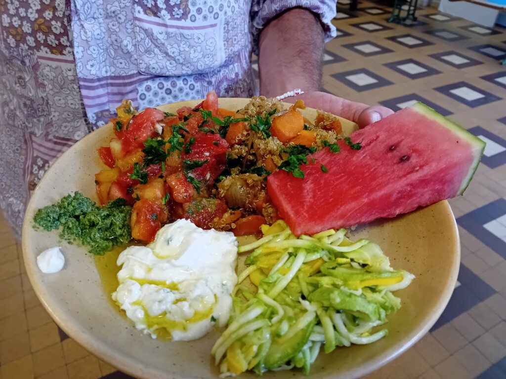 Assiette etivale : salade de courgettes rapés, sauce yaourt aux herbes, pesto, salade de tomates, quinoa aux petits légumes, tranche de pastèque.